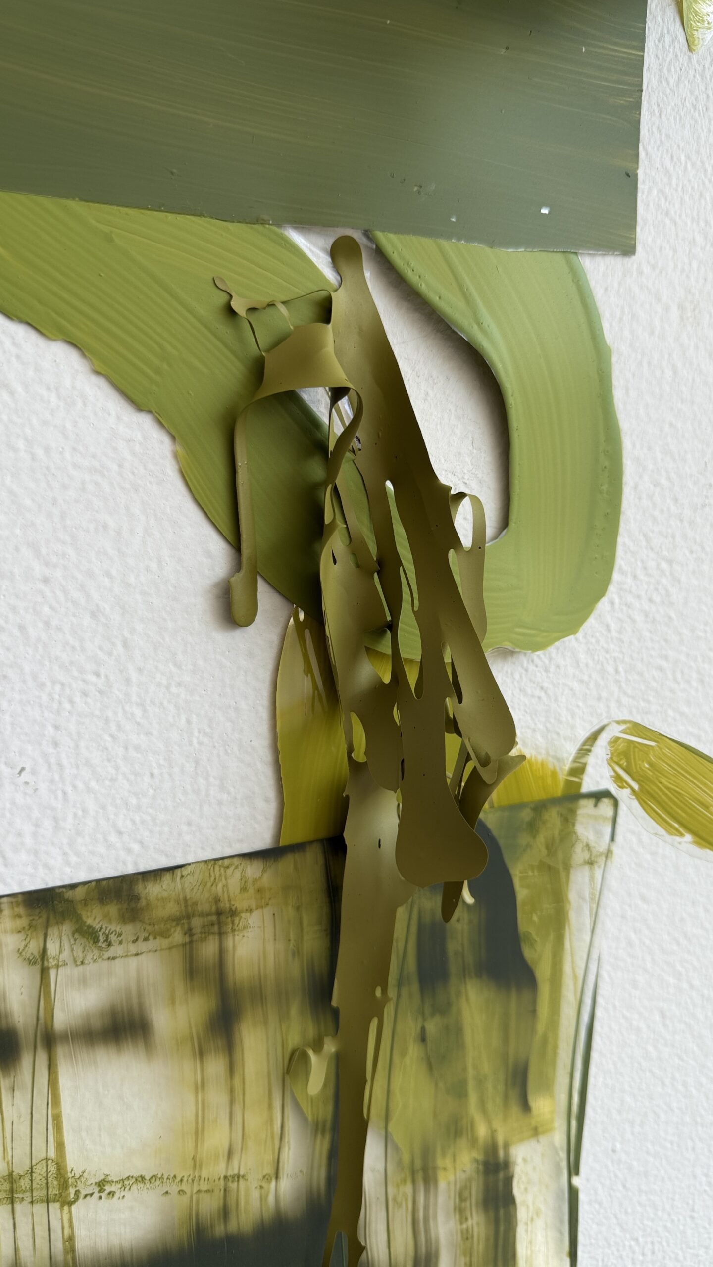 Detalle de la obra de Gabriela Sánchez con láminas verdes y amarillas, pliegues y marcas sobre fondo blanco.